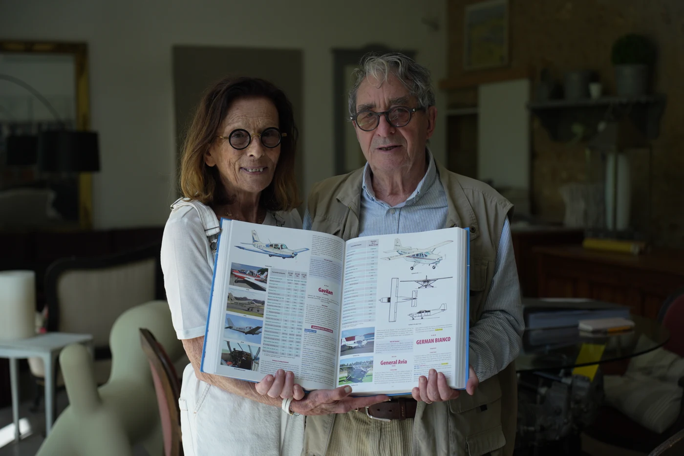 Marc et Geneviève Ranjon montrent une double page de l’encyclopédie avec photographies, plans et caractéristiques des avions